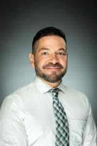 Head shot of Dr. Josh Matacotta, wearing a collared shirt and tie.