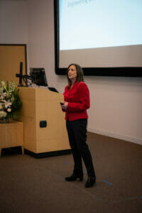 Dr. Sandra Block standing next to a podium giving a lecture.