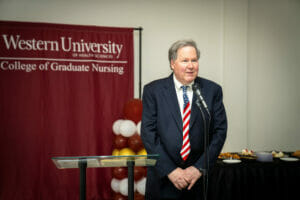 Dr. Rod Hicks wearing U.S. flag tie speaks at microphone.