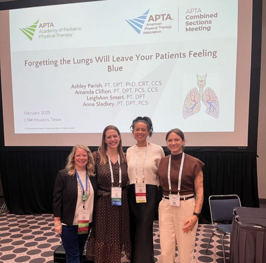 Four people stand together in front of a projector screen displaying a presentation titled "Forgetting the Lungs Will Leave Your Patients Feeling Blue" at the APTA Combined Sections Meeting.