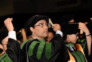Graduates in caps and gowns move their tassels during a commencement ceremony.