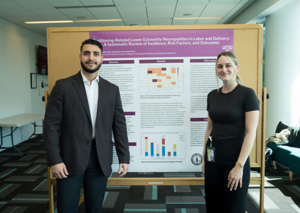 Two people stand in front of a scientific poster about lower extremity neuropathies in labor and delivery, displayed on a corkboard in a conference setting.