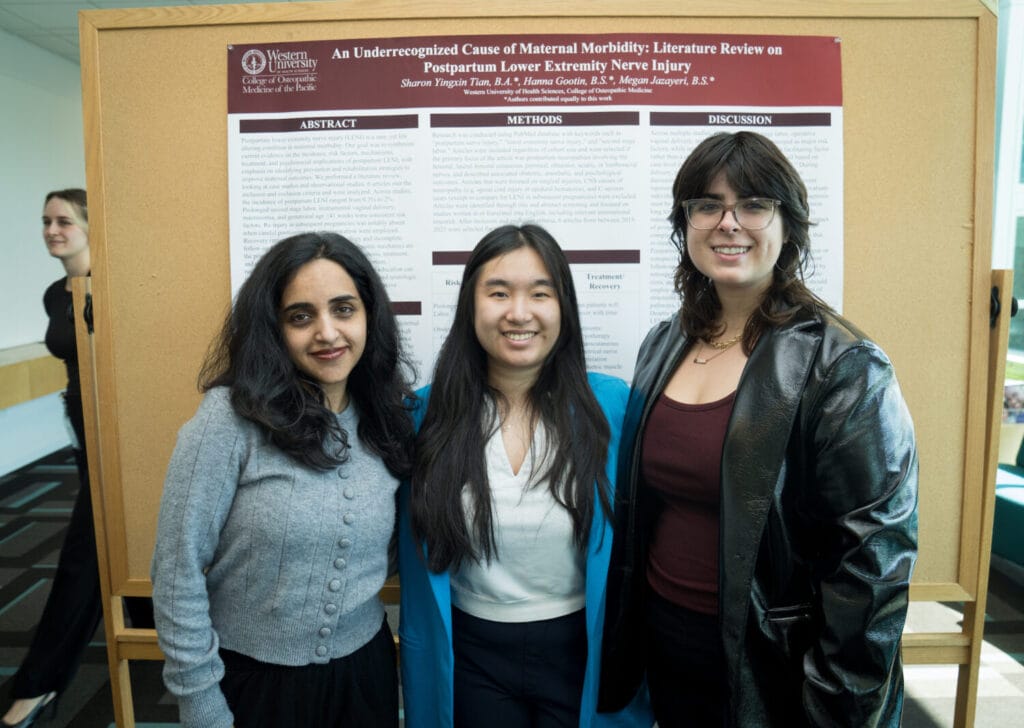 Three women stand in front of a scientific research poster on postpartum lower extremity nerve injury at a conference or academic event.