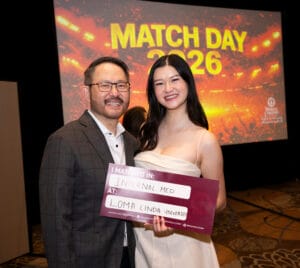 Two people stand indoors, smiling at the camera. One holds a sign that reads, "I matched in: Internal Med at: Loma Linda University." A "Match Day 2026" screen is visible behind them.
