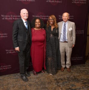 Four individuals pose together at an event hosted by Western University of Health Sciences, standing in front of a branded backdrop.