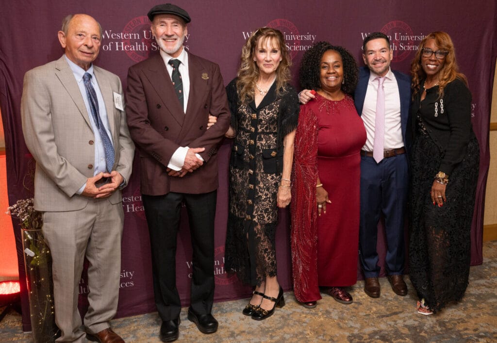 Six individuals pose together at an event hosted by the Western University of Health Sciences, standing before a branded backdrop.